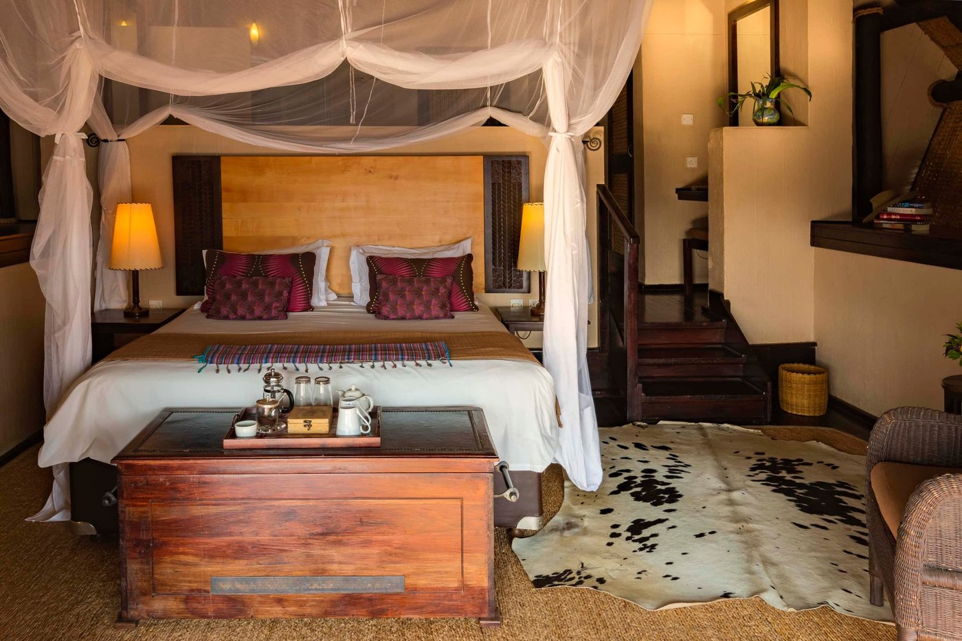 Hemelbed met klamboe en donker houten meubilair bij Chilo Gorge Safari Lodge.