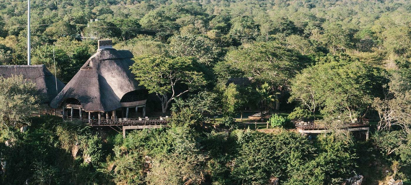 Rieten lodgegebouw op een verhoogd terras boven de beboste gorge bij Chilo Gorge Safari Lodge.