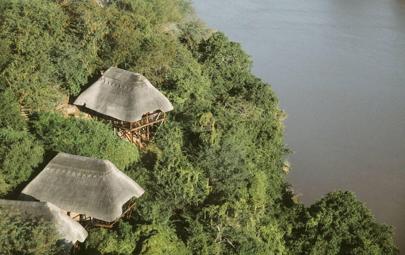 Rieten gastenkamers op palen boven de Save River-klif bij Chilo Gorge Safari Lodge.