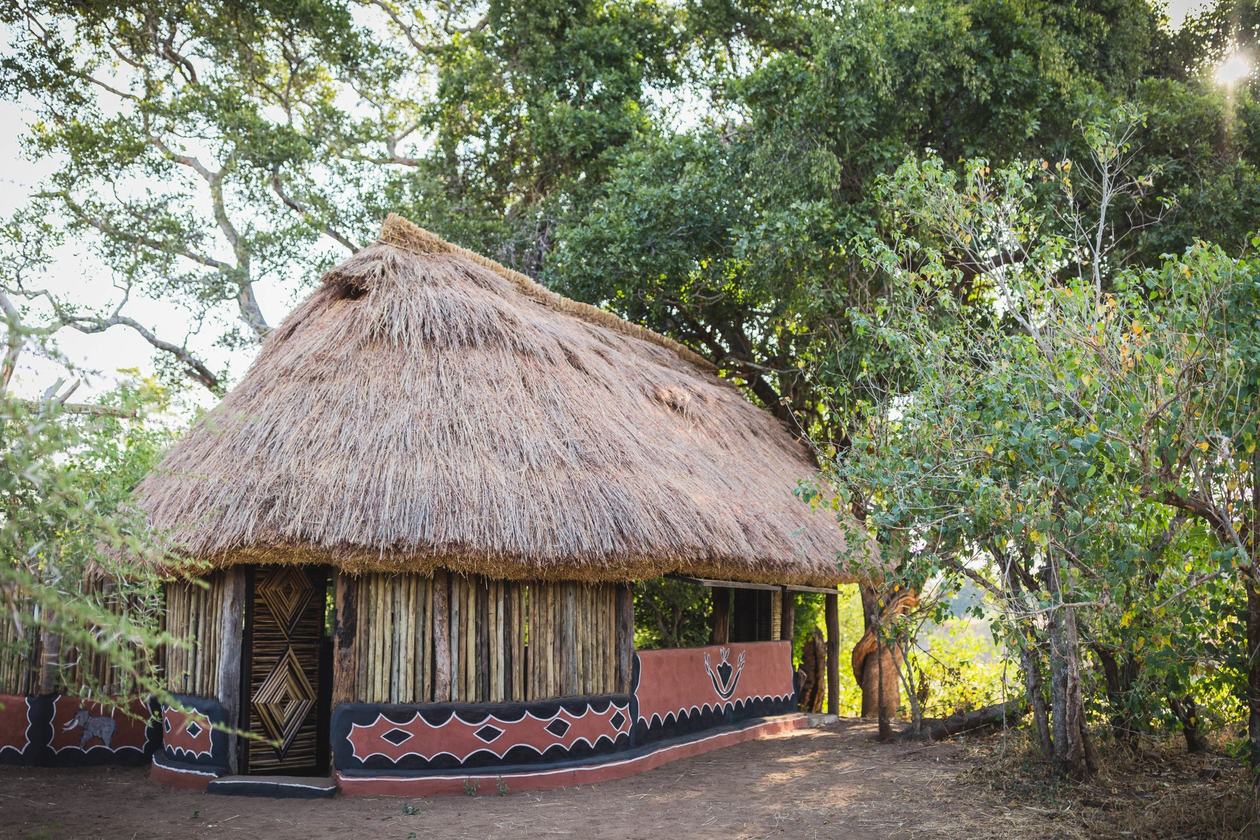 Een ronde moddersteenhut met beschilderde muren staat beschut bij Mananga Camps.