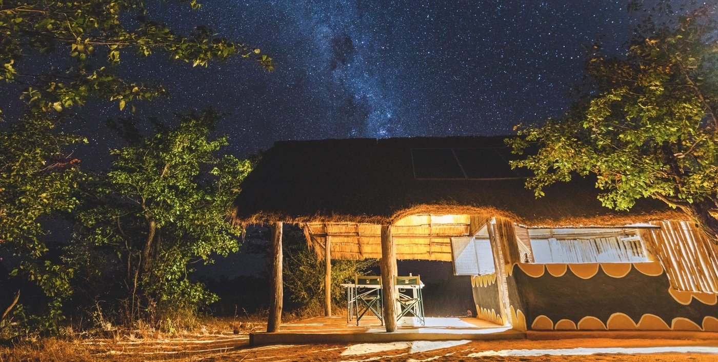 Warm licht stroomt uit een huisje onder de Melkweg bij Mananga Camps.